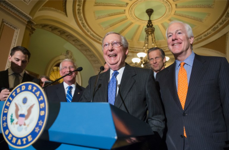 Mitch McConnnell stands behind a podium in 2016, surrounded by Congressional colleagues.