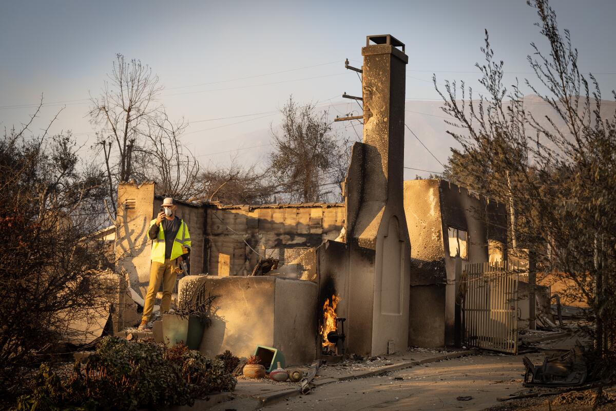 George Cunningham wears a bright yellow vest and walks through the rubble of his home.