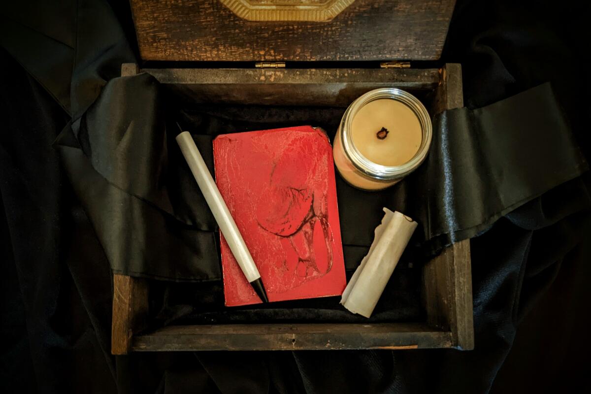 A box with a notebook, candle and scrolled parchment. 