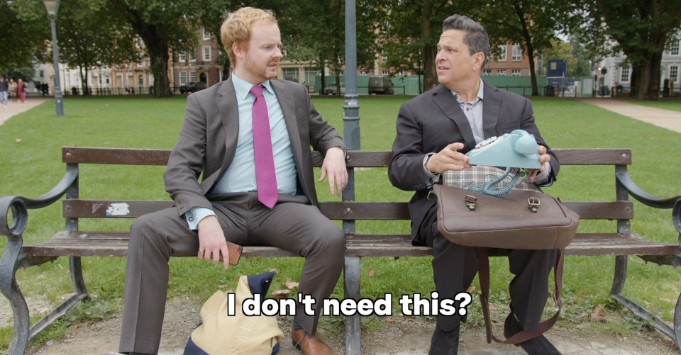 Two men sitting on a park bench, one holding a vintage phone.  "I don't need this?" is overlaid on the image.