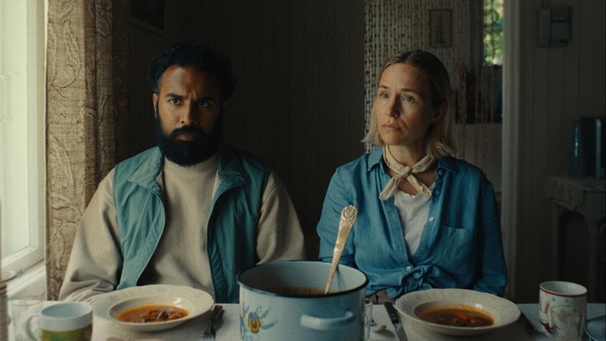 A couple sits at a table eating vegetable soup.