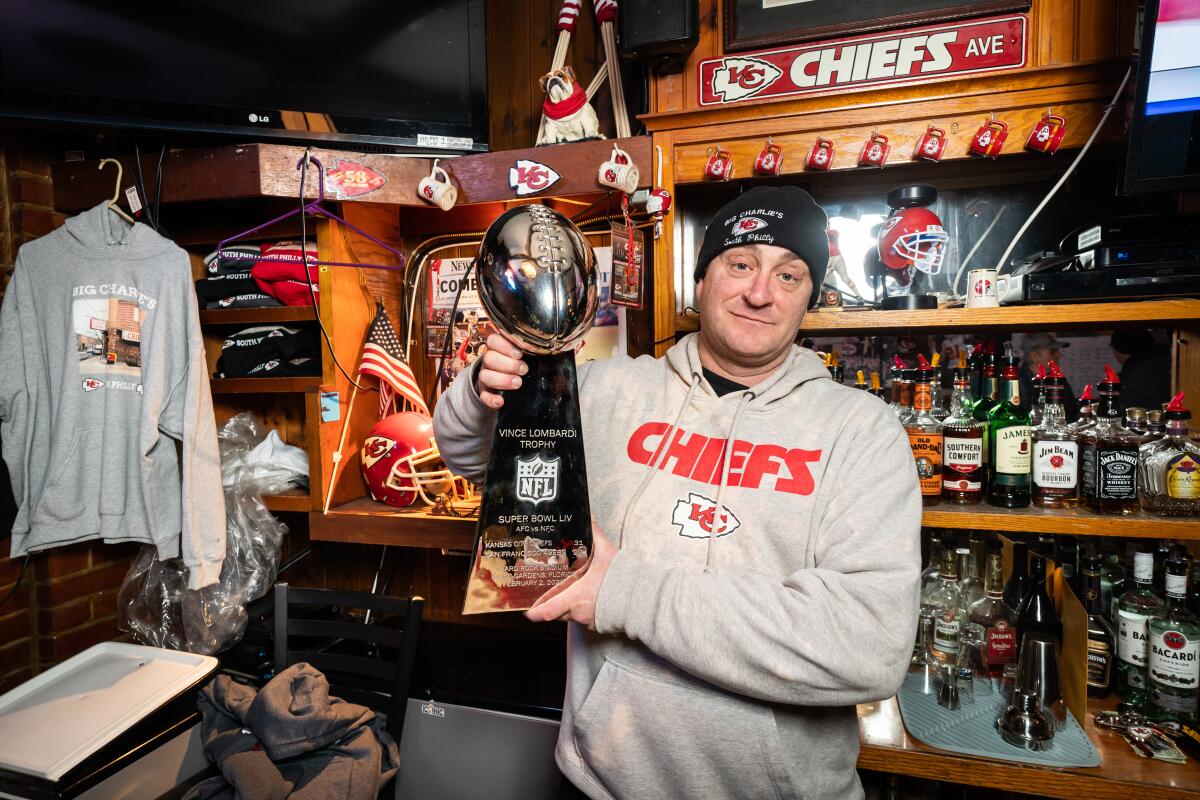 Michael Puggi holds a replica of the Lombardi Trophy that was gifted to Big Charlie's Saloon.