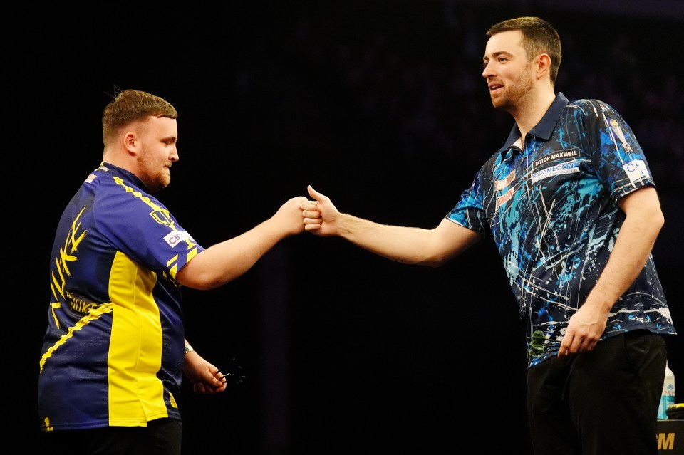 Luke Littler and Luke Humphries fist-bumping at a darts match.