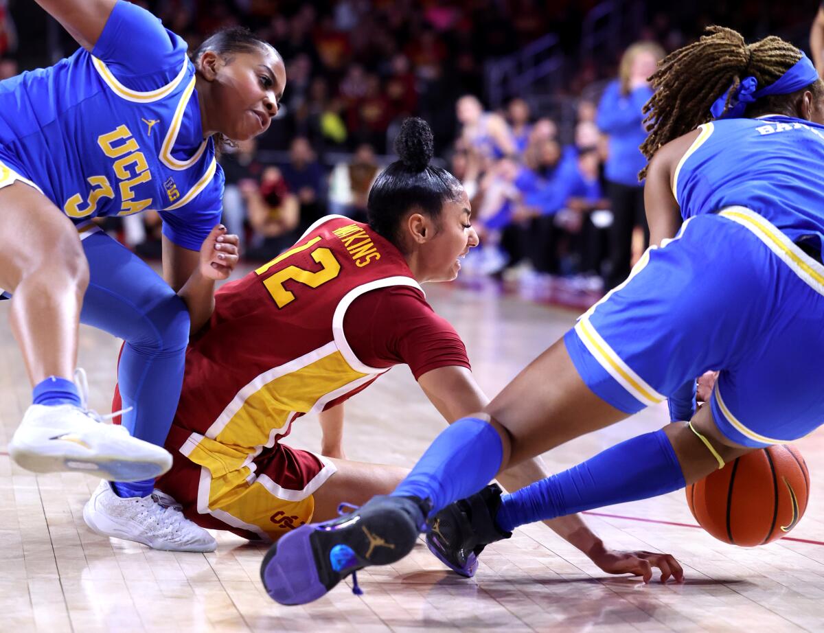 USC's JuJu Watkins, center, battles UCLA's Londynn Jones, left, and Janiah Barker for a loose ball.