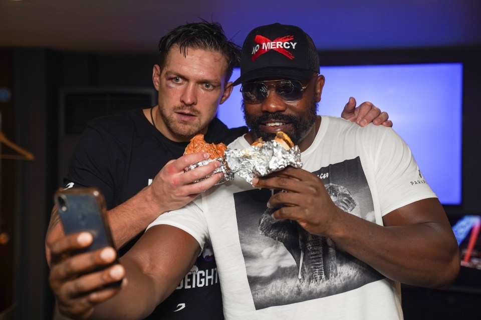 Two boxers sharing a selfie while eating burgers.