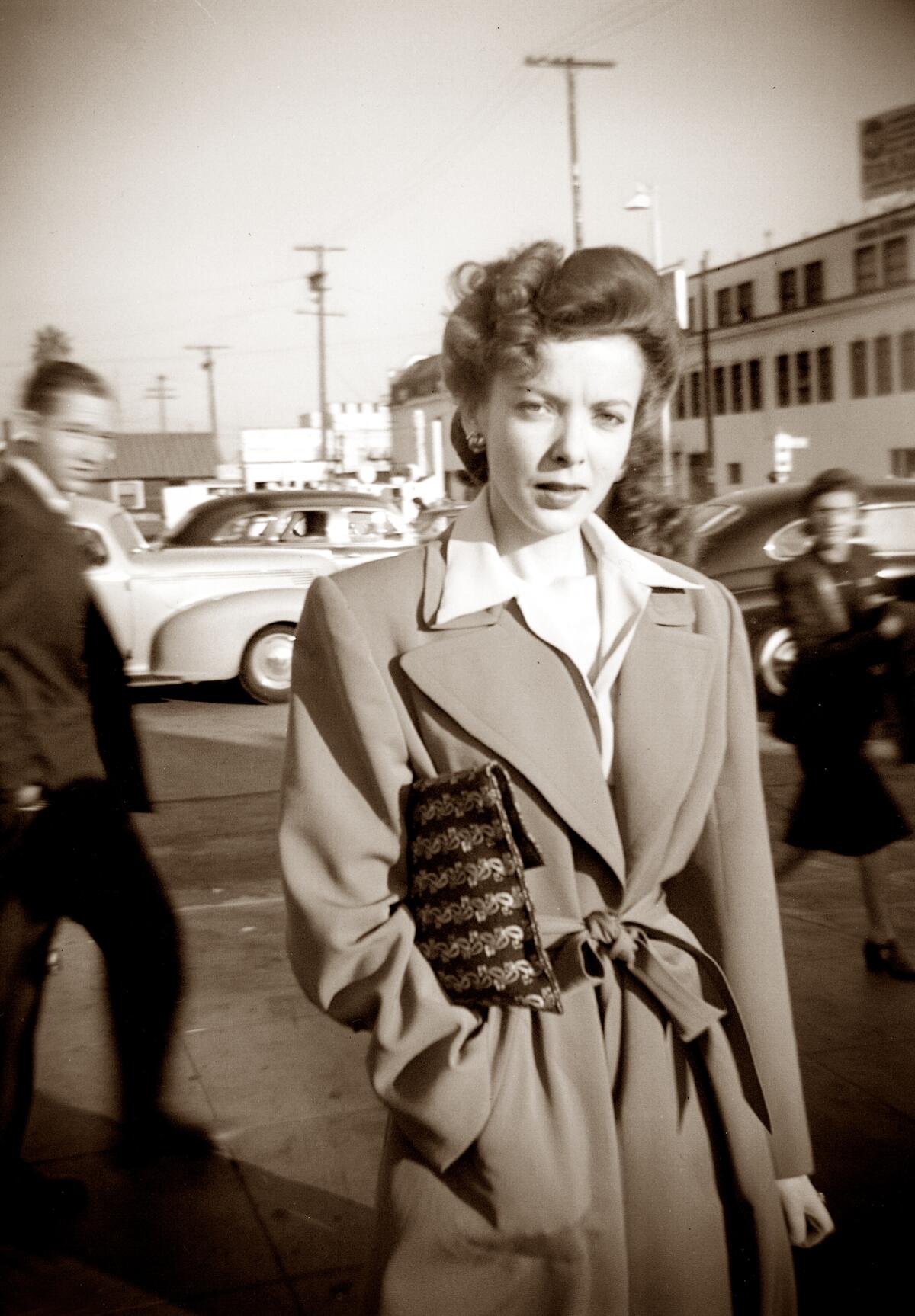 A woman poses on a city street.