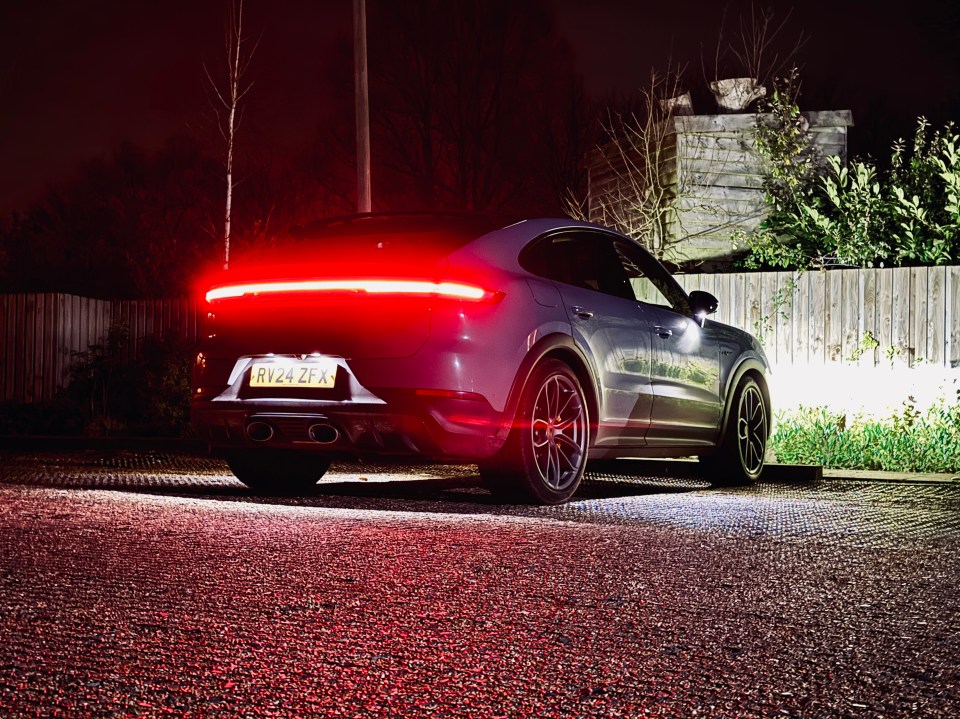 Rear view of a grey Porsche Cayenne at night.