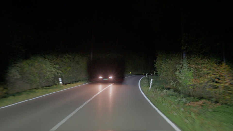 Car driving on a dark road at night.