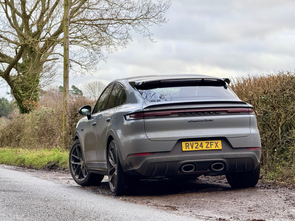 Rear view of a gray Porsche Cayenne parked on a country road.