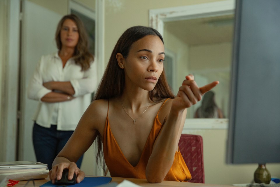 Zoe Saldaña and Karla Sofía Gascón at a dinner table in a scene from *Emilia Pérez*.