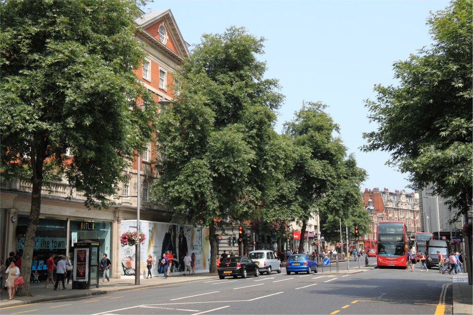 Kensington High Street in London, with shops, buses, and taxis.