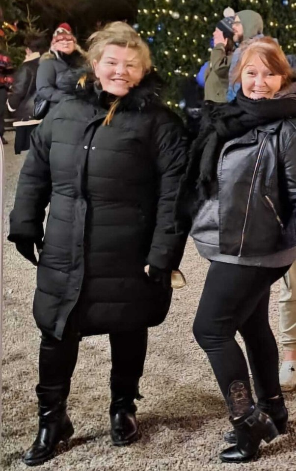 Two women in winter coats standing in front of a Christmas tree.