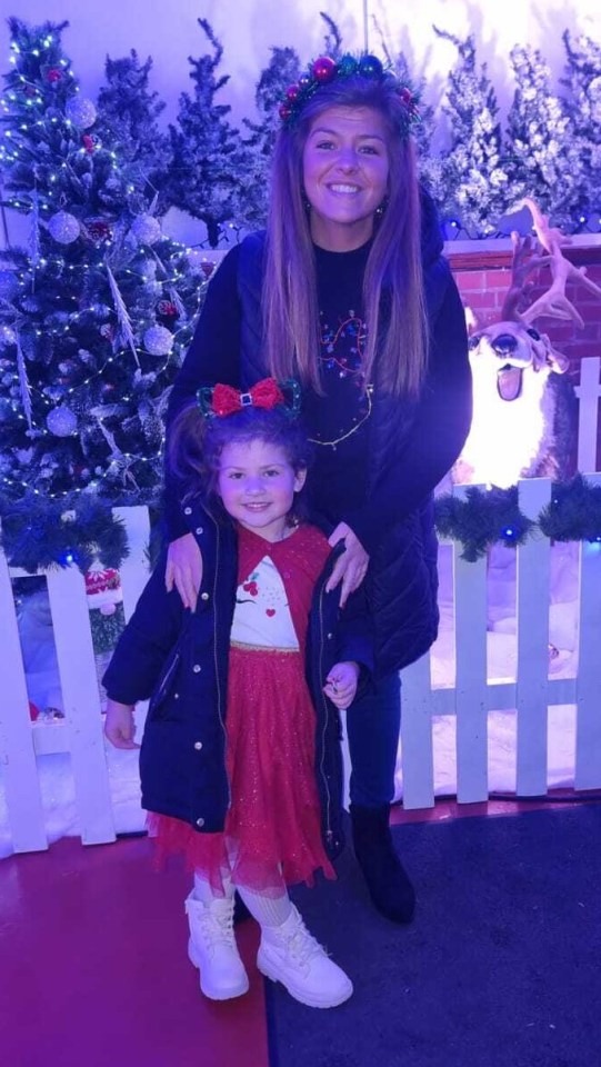 A mother and daughter posing in front of a Christmas display.