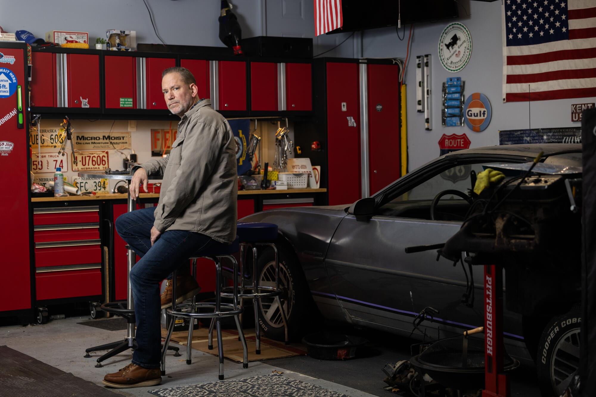 Dan Osborn sits in his garage beside a 1988 Pontiac Firebird.