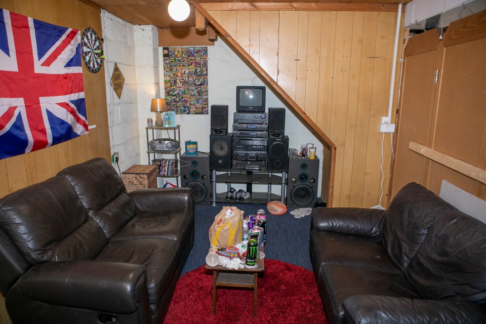 Basement room with two leather couches, a stereo system, and a dartboard.