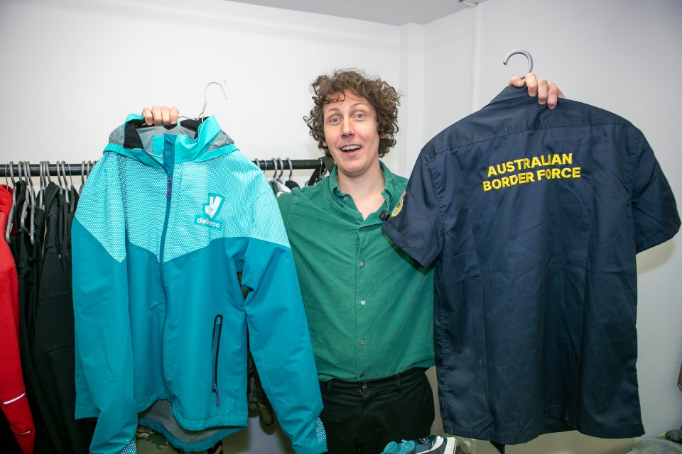 Man holding up a teal jacket and an Australian Border Force shirt.