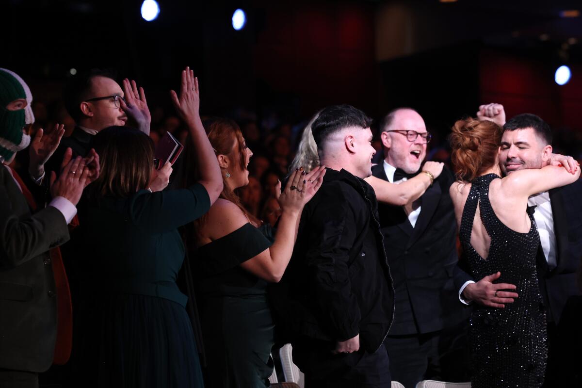 A creative team leaps to its feet in joy at an awards show.