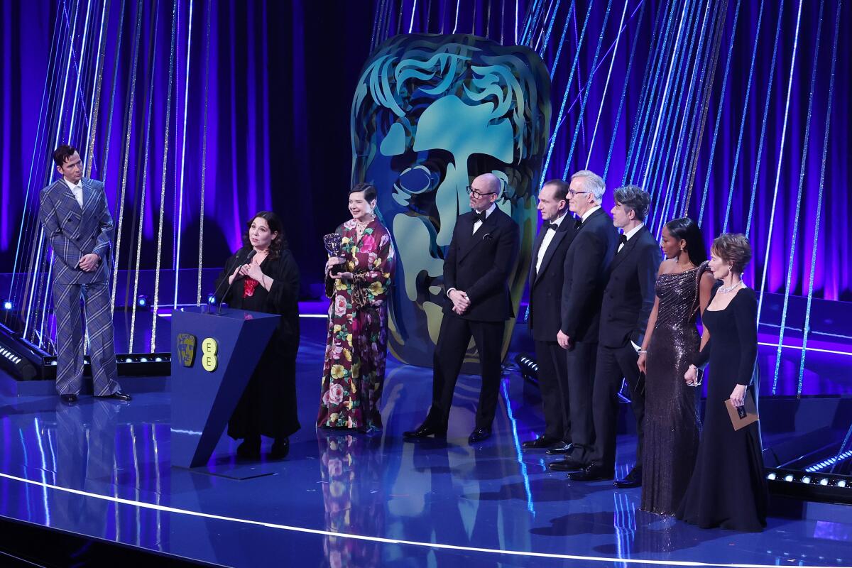 Several members of a creative team accept an award onstage.