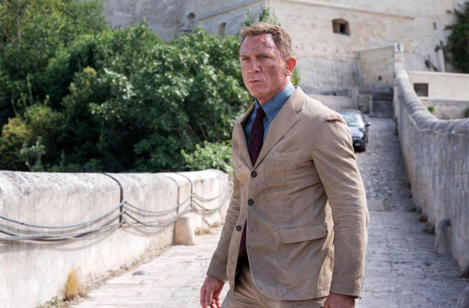 Daniel Craig in a tan suit in a scene from No Time To Die.