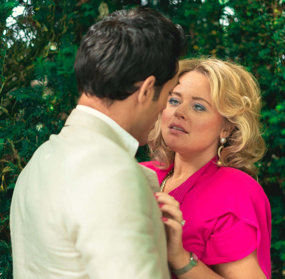 A man and woman facing each other in front of a hedge.