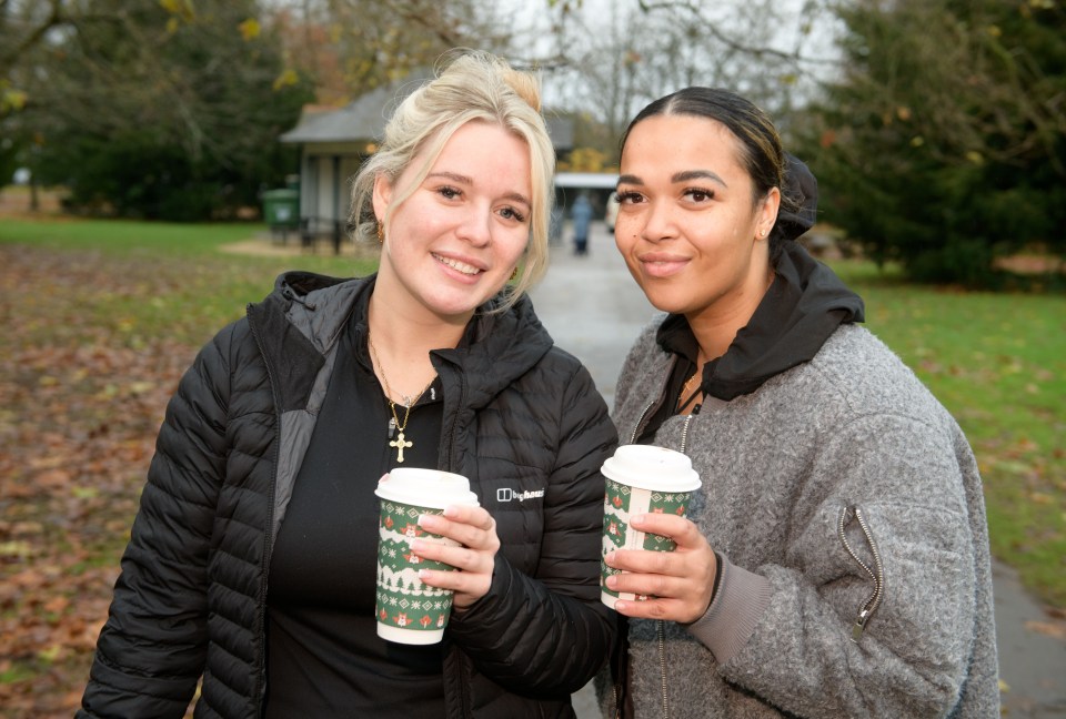 Two women holding coffee cups in a park.