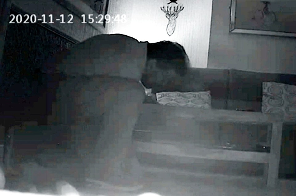 Low-light security camera footage of a person retrieving a recording device.