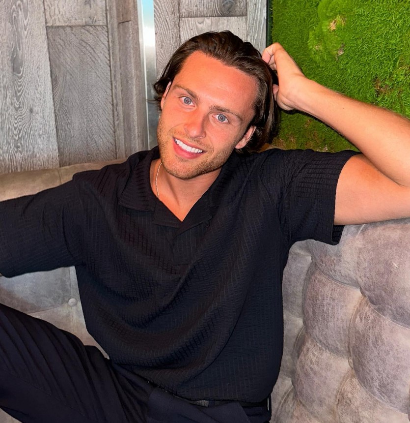 Man in black shirt smiling.