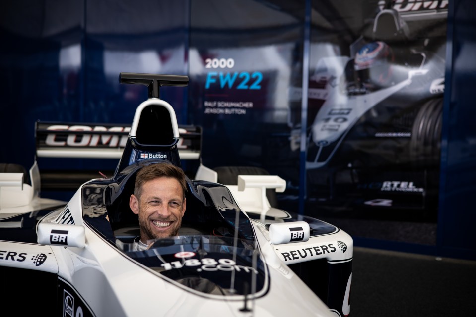 Jenson Button smiling in a Formula One race car.