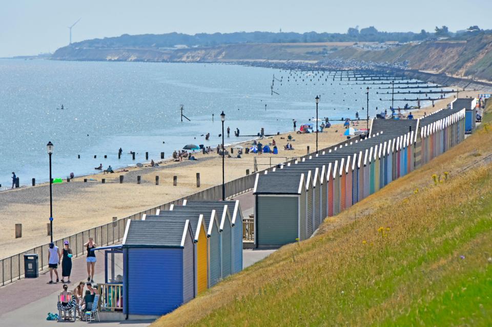 Beach scene with colorful beach huts and people on the sand.