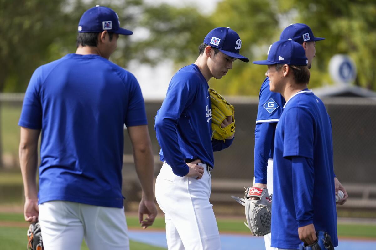 Dodgers two-way star Shohei Ohtani, left, pitcher Roki Sasaki and pitcher Yoshinobu Yamamoto stand on a practice field.