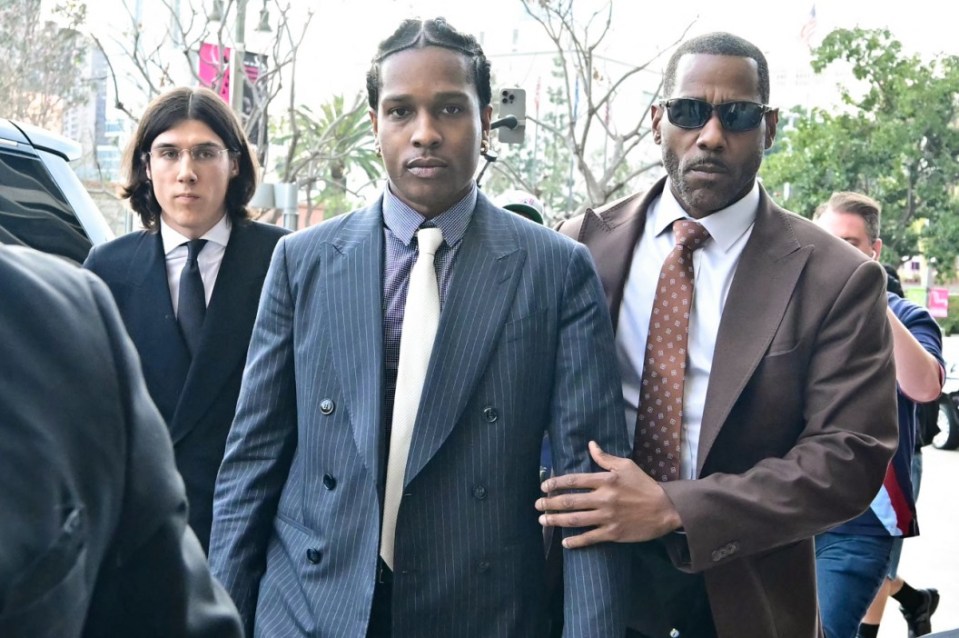 A$AP Rocky arriving at court, escorted by a man in a brown suit.