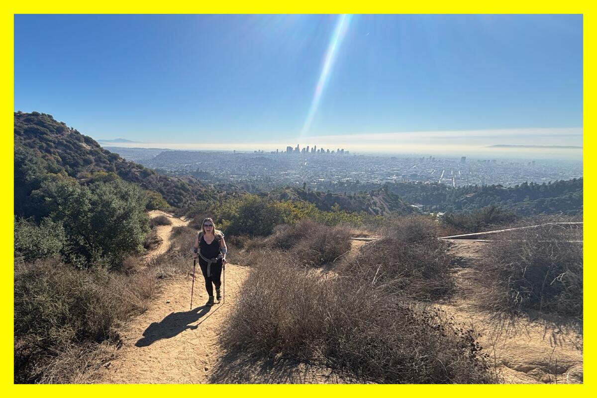 A hiker on Hogback Trail in Griffith Park. Skyscrapers can be seen in the distance.