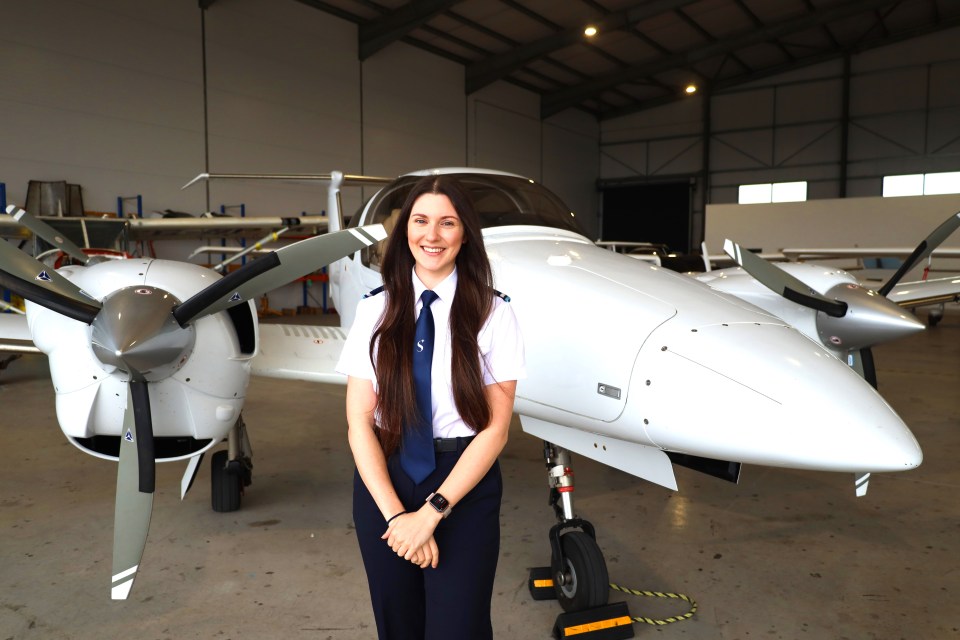 Female pilot standing in front of a small airplane.