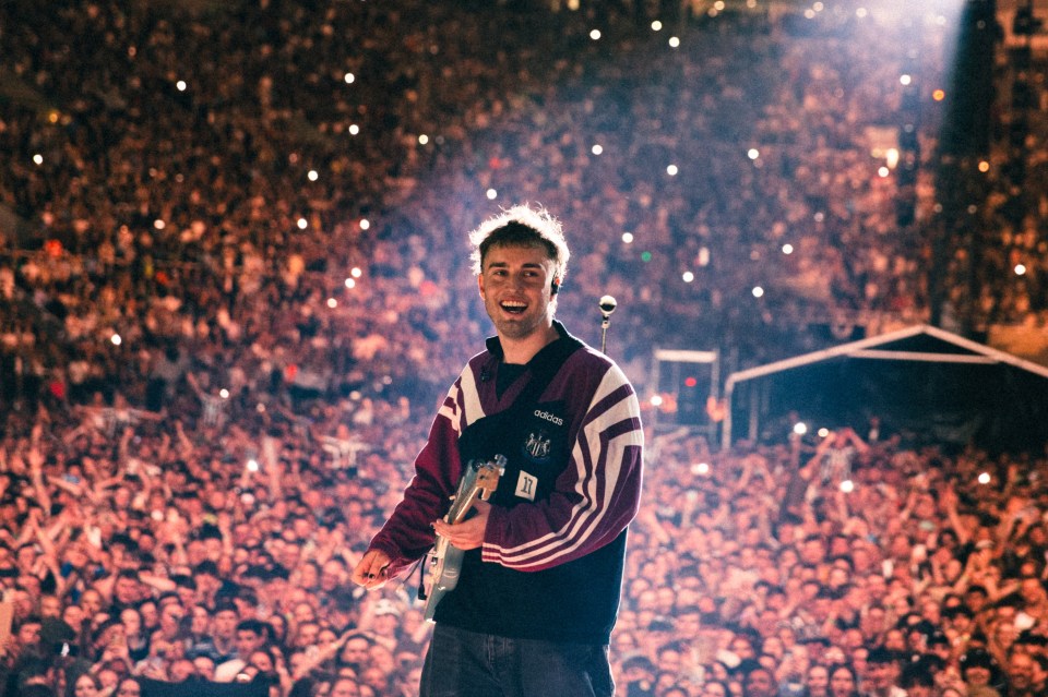 Sam Fender performing on stage in front of a large crowd.