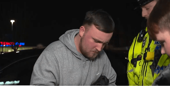 Man being questioned by police officers at night.