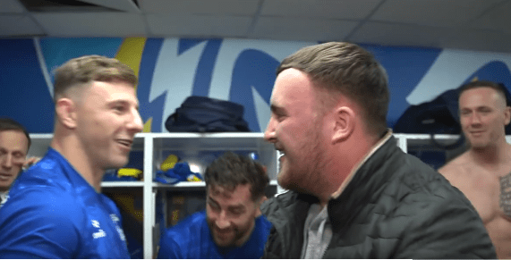 Two men laughing in a locker room.