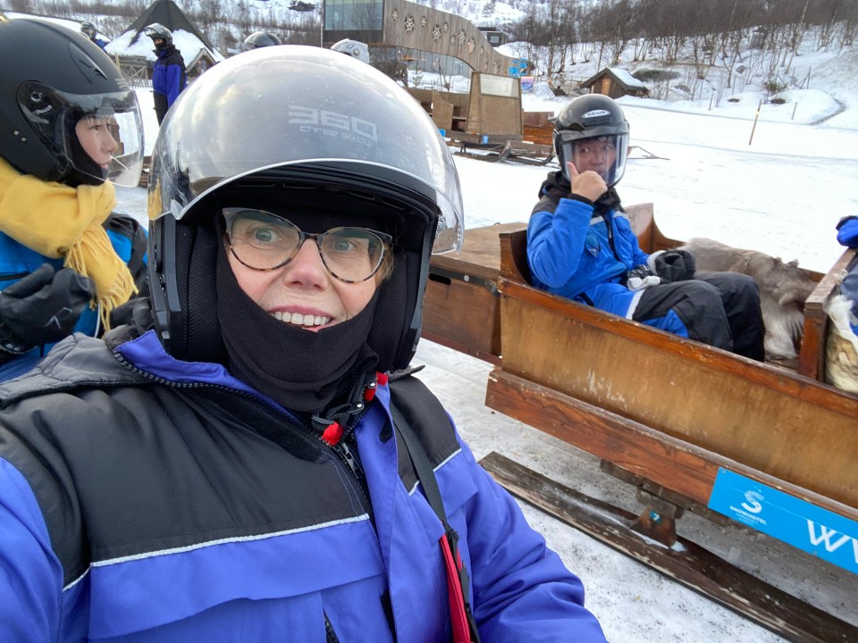 Woman in a helmet on a reindeer sleigh ride.