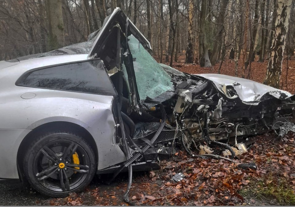 Severely damaged silver Ferrari in a forest.