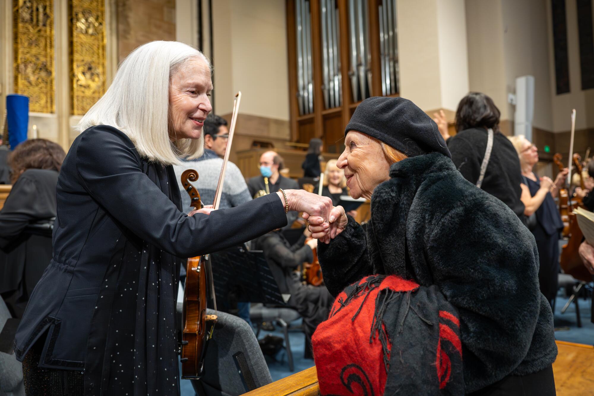 Palisades Symphony violinist Helen Bendix is congratulated by Lynda Jackson after the symphony's performance.