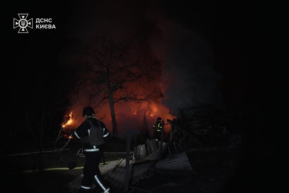 Firefighters extinguishing a fire in Kyiv at night.