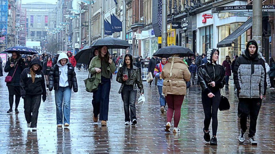 People walking down a rain-slicked city street.