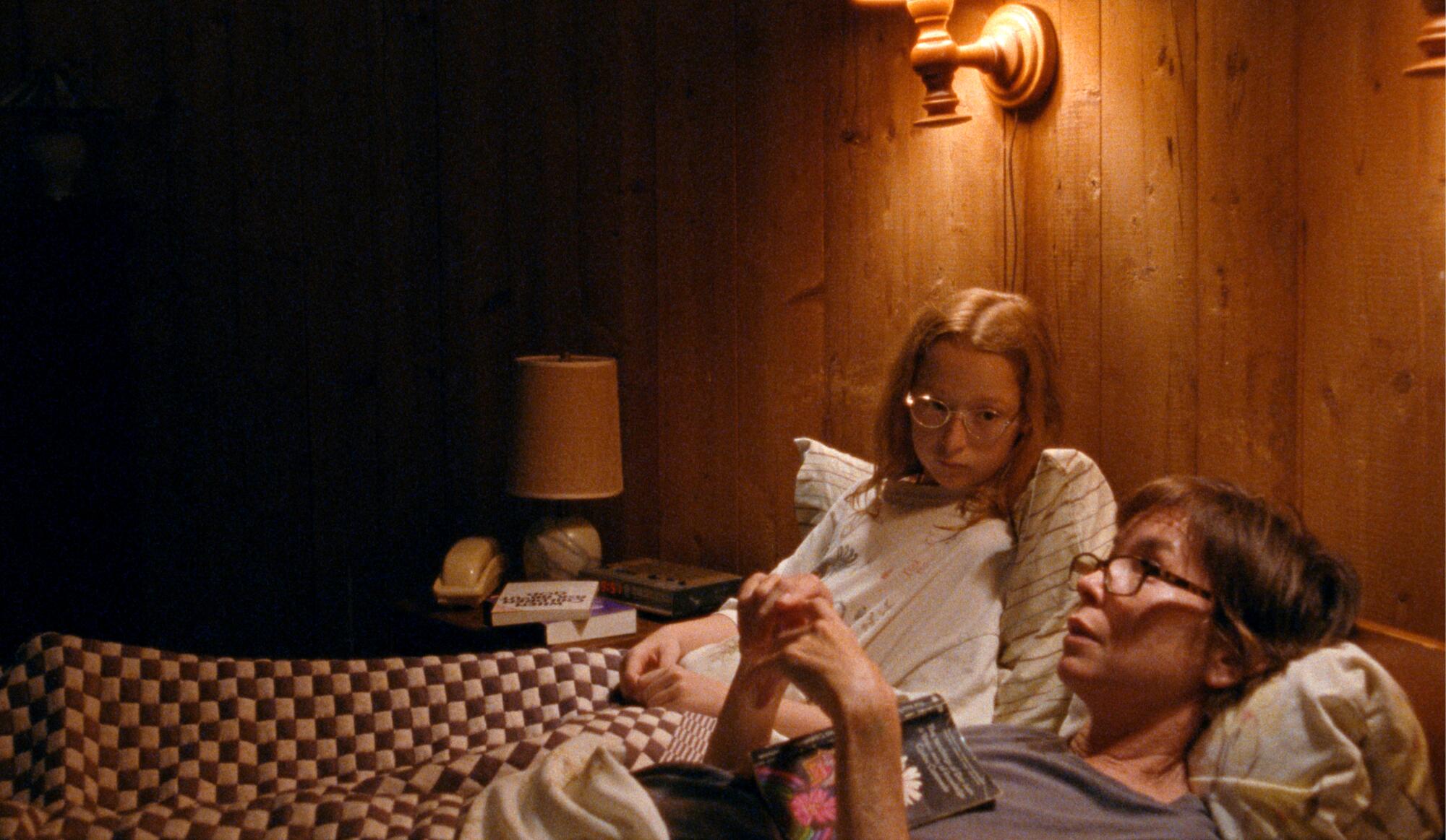 A young girl sits in bed with her mother.