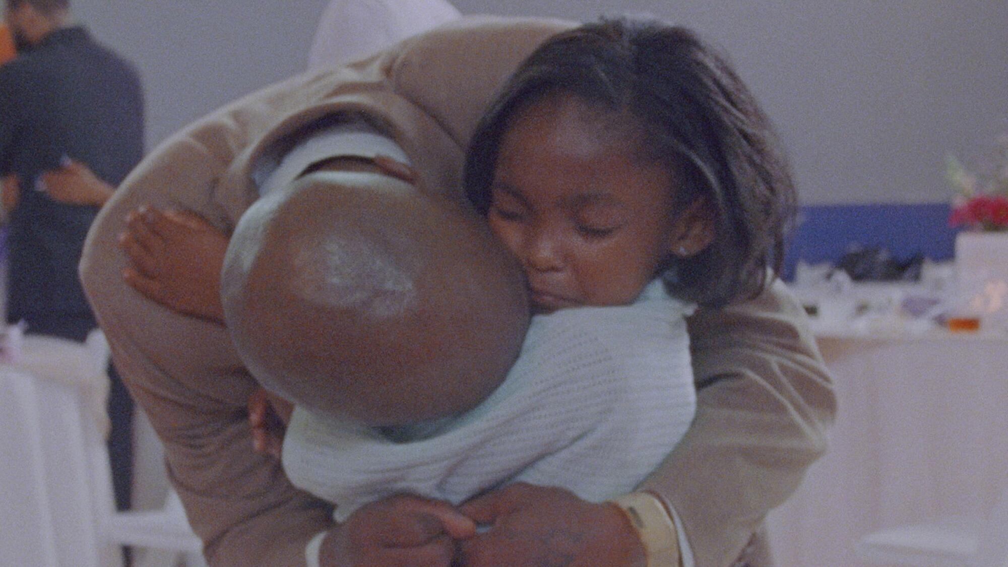 A father hugs his young daughter.