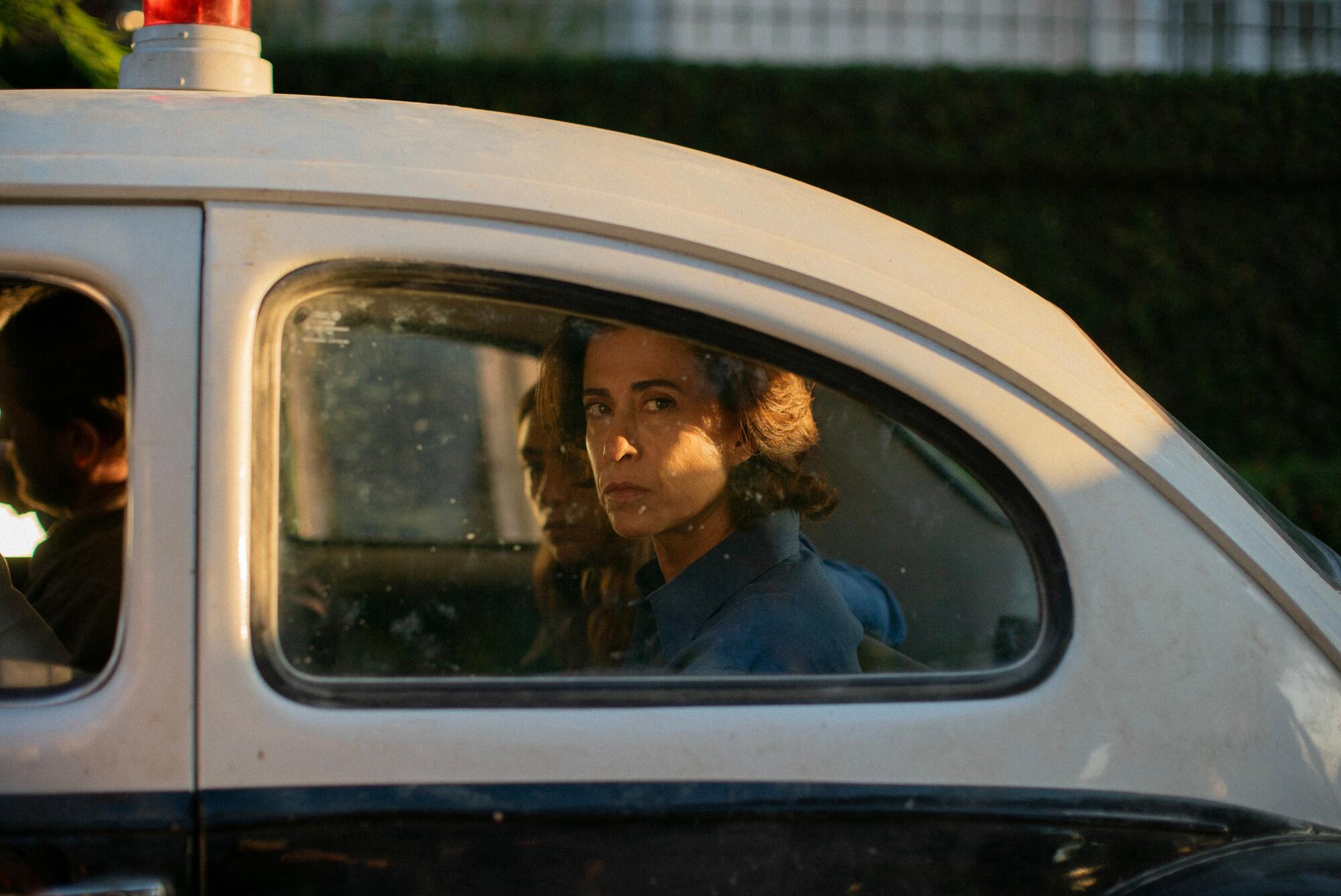 A woman in a car looks out the window.