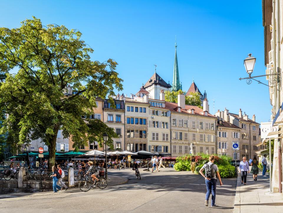 Place du Bourg-de-Four in Geneva's old town, with old buildings, cafes, and pedestrians.