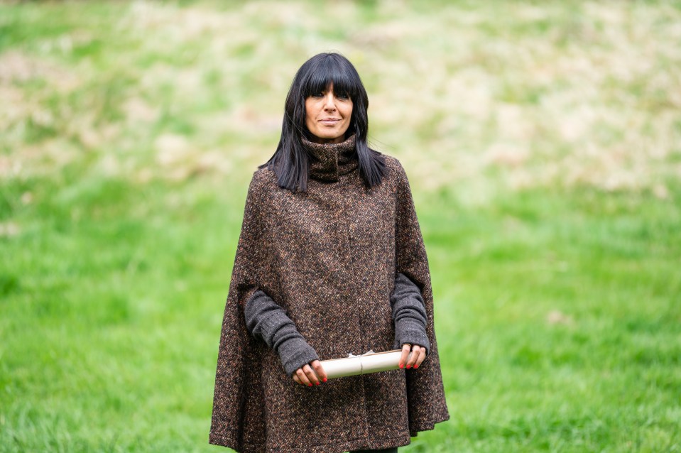 Claudia Winkleman holding a clutch in a field.