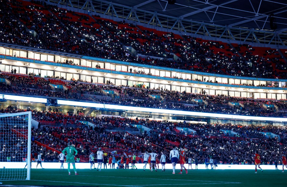 Wembley Stadium crowd holding up lit phones during a power outage at a women's soccer game.