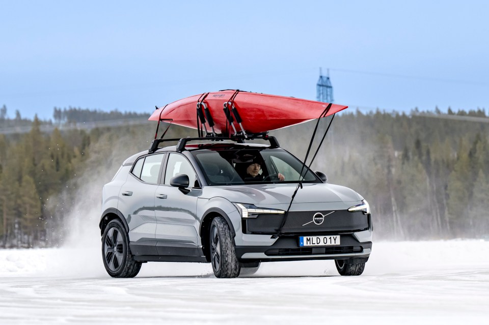 Grey Volvo SUV driving on ice with a red kayak on the roof rack.