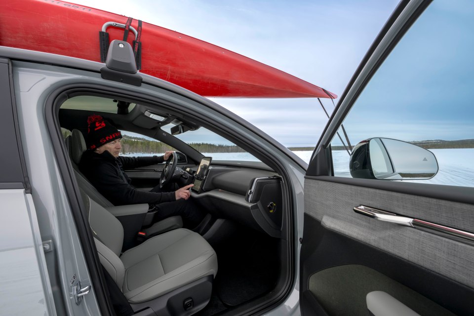 Person using the infotainment system in a car with a kayak on the roof.