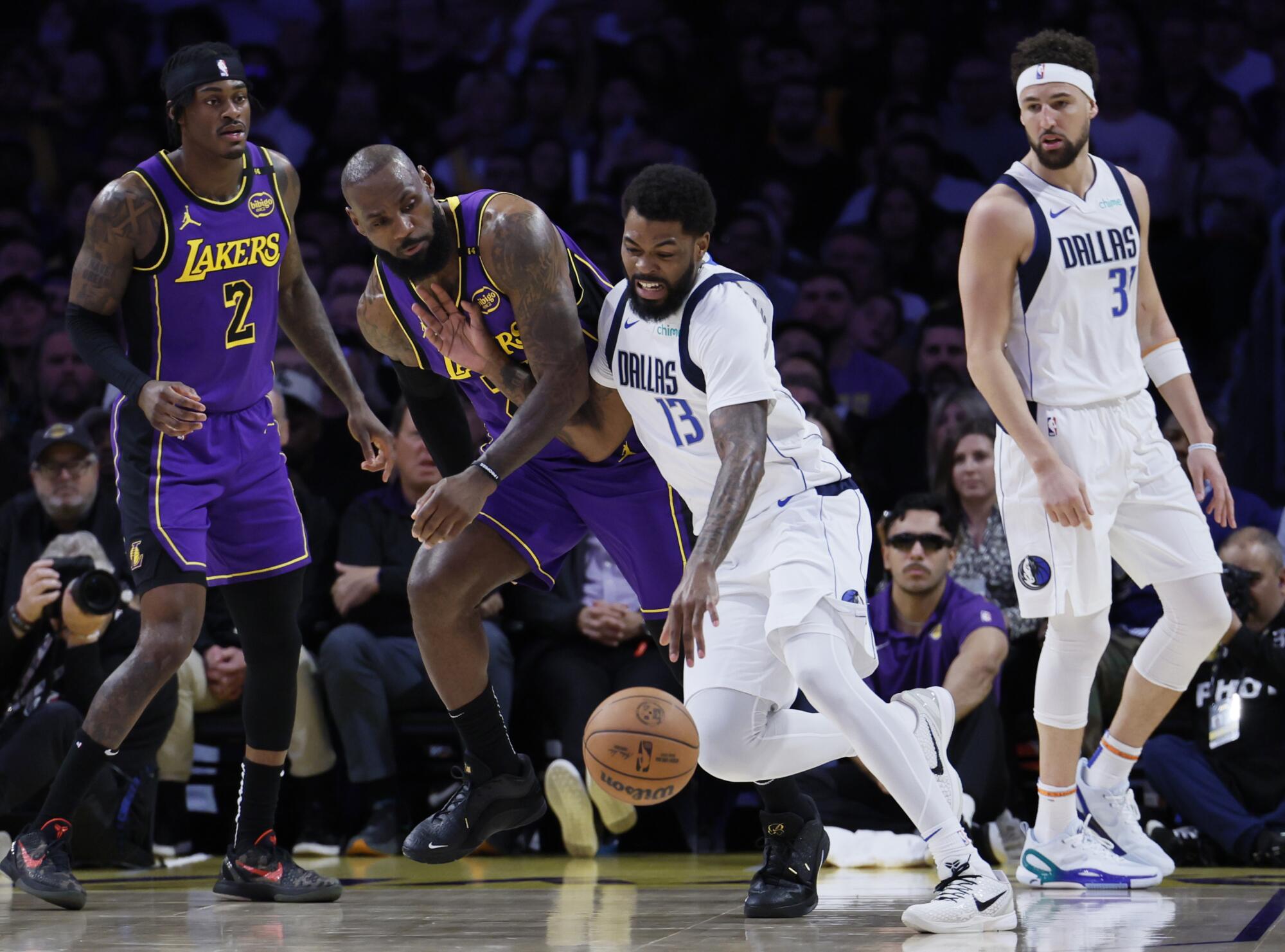 Lakers forward LeBron James, center left, guards Mavericks forward Naji Marshall at Crypto.com Arena on Tuesday.